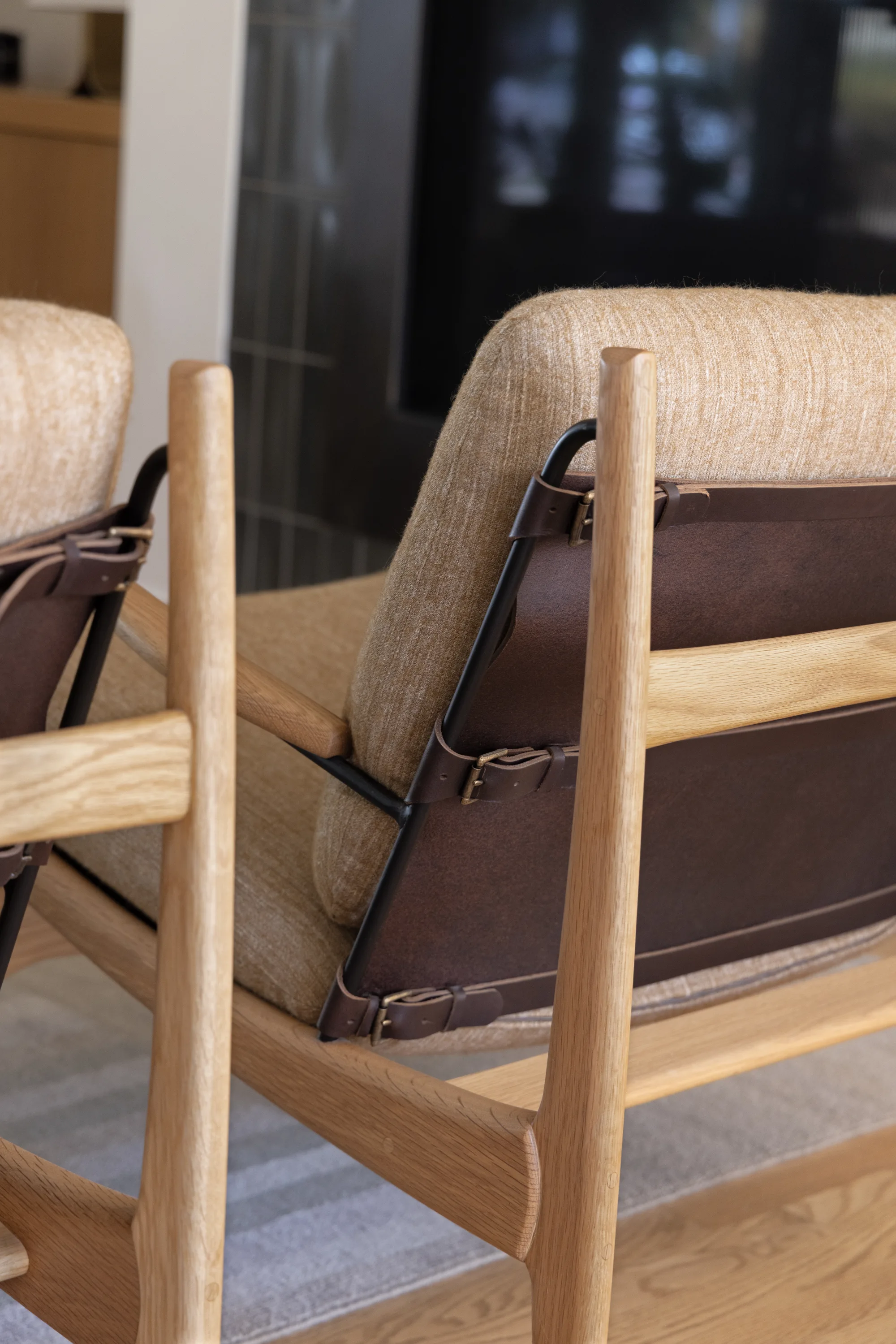 Detail of a wood lounge chair with leather straps and a linen cushion
