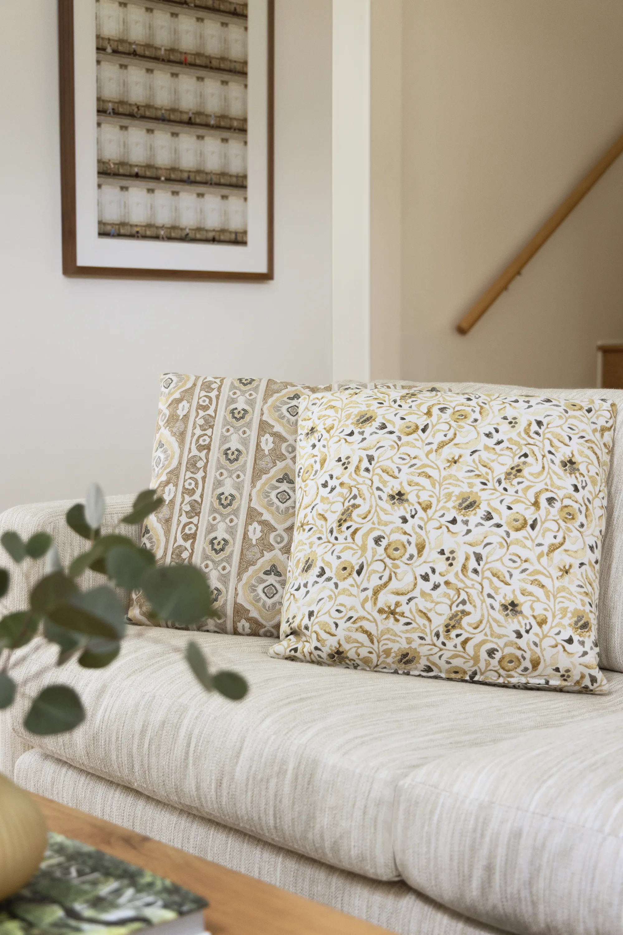 Patterned pillows on a cream sofa beneath framed artwork