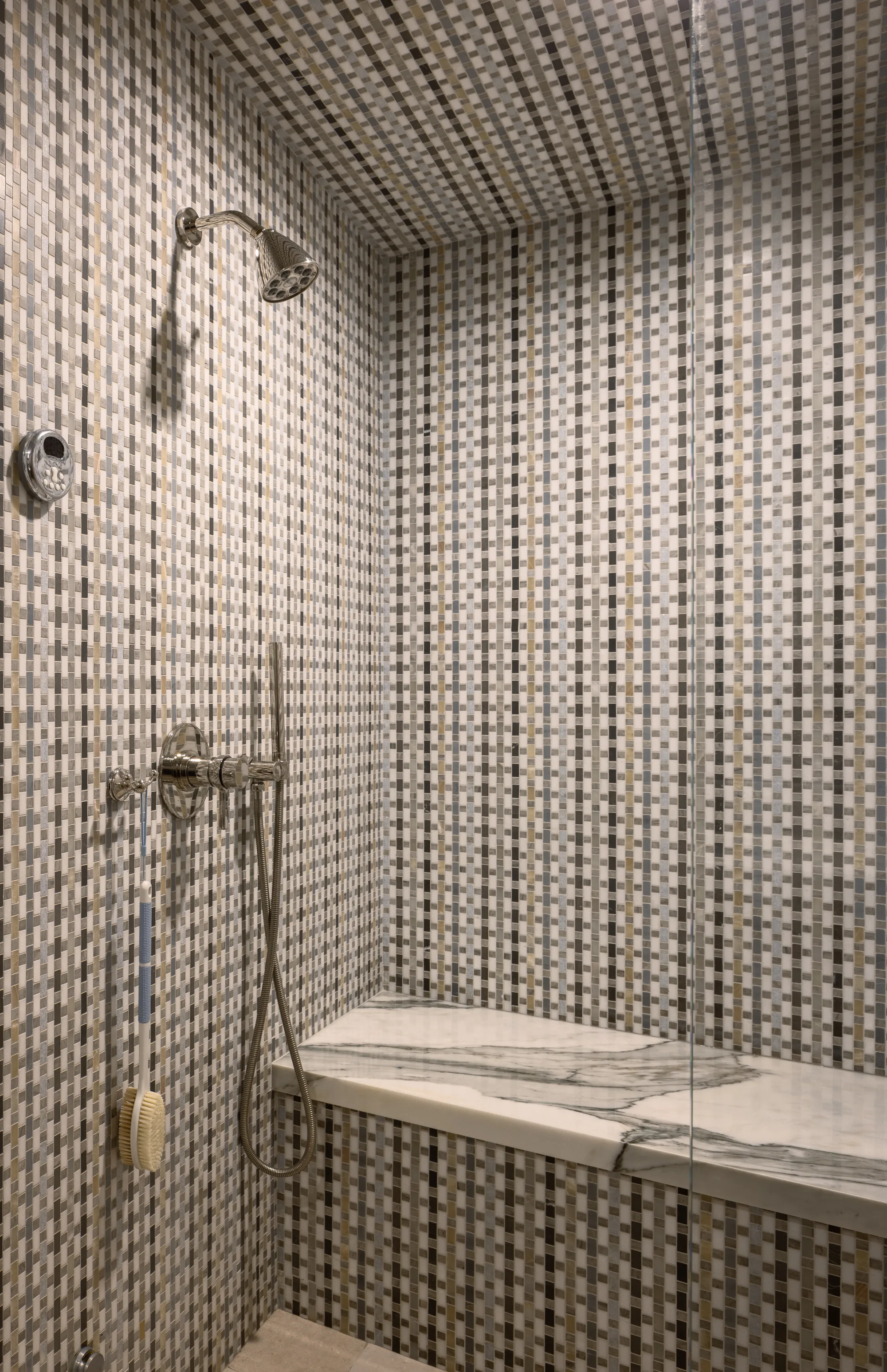 Steam shower clad in patterned tile with a marble bench